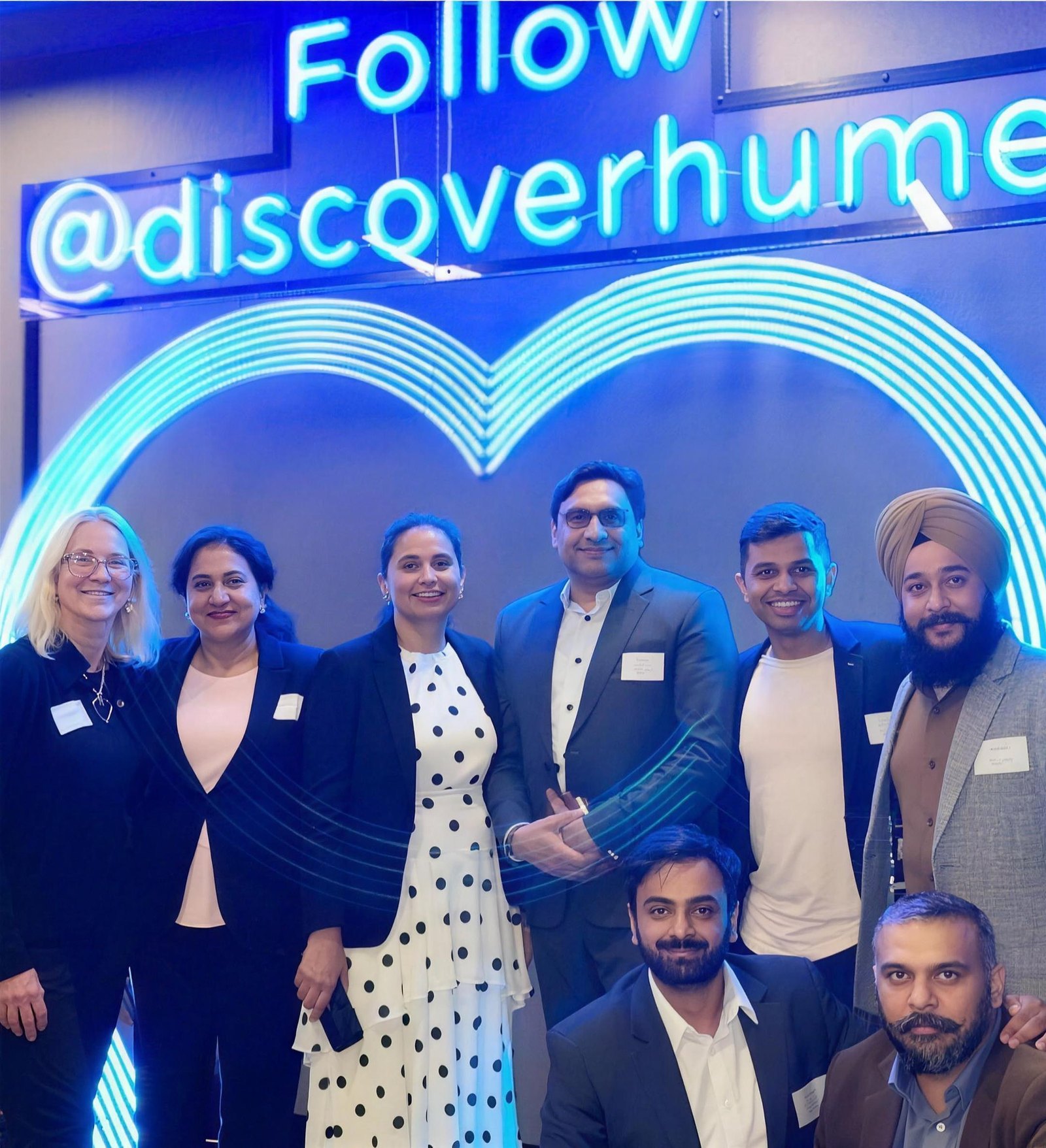 A group of professionals poses at an event promoting Discover Hume, showcasing compliance services.