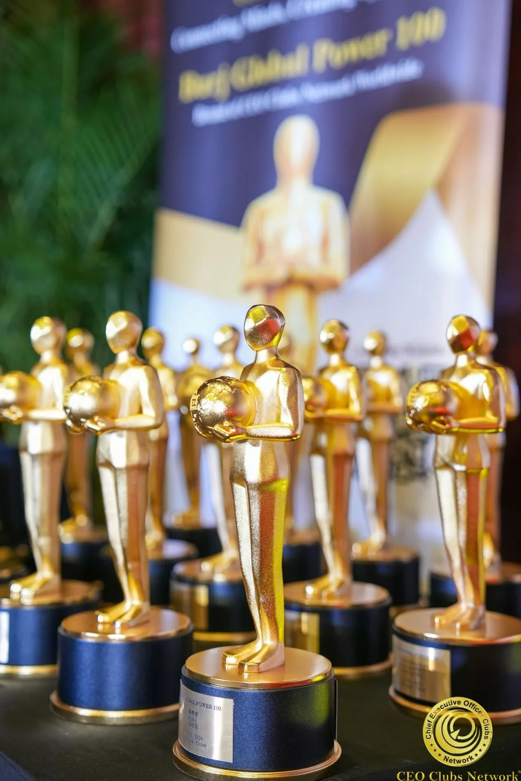 Golden Burj Global Power 100 trophies are displayed at an event, recognizing business leadership and international.