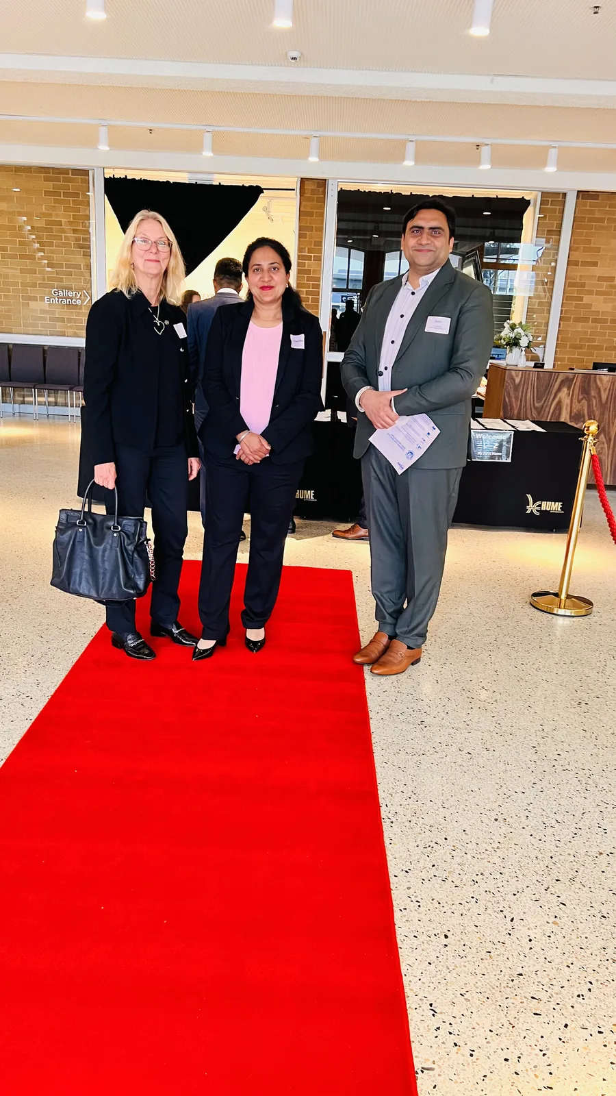 Sukh Sandhu with colleagues on a red carpet at an event, showcasing professional development.