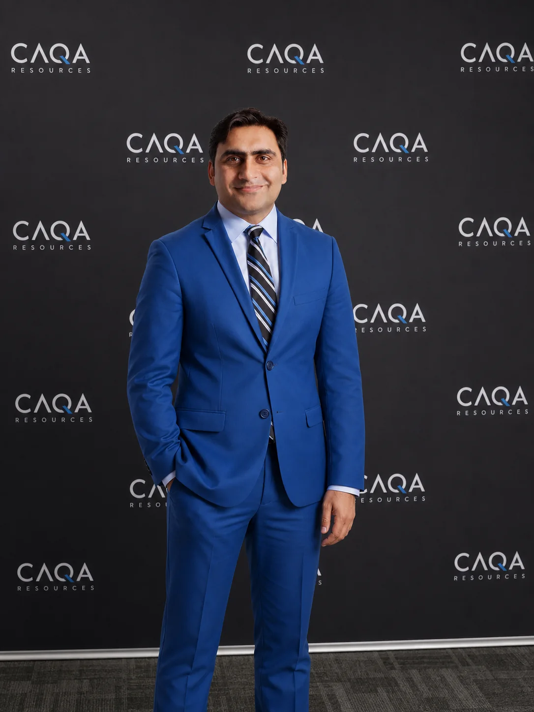 Sukh Sandhu, a UN Representative and ISO Auditor, poses at a corporate event with CAQA Resources branding.