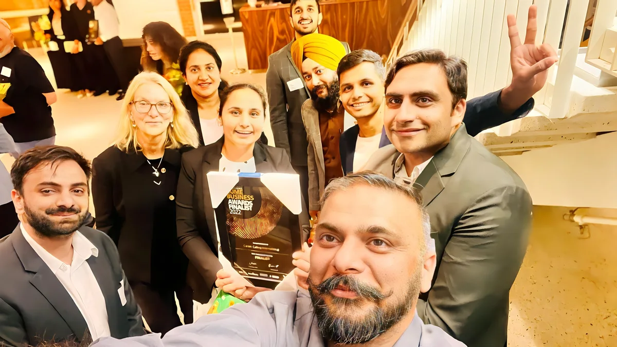 A team celebrates winning a business award, showcasing Sukh Sandhu's commitment to quality assurance.