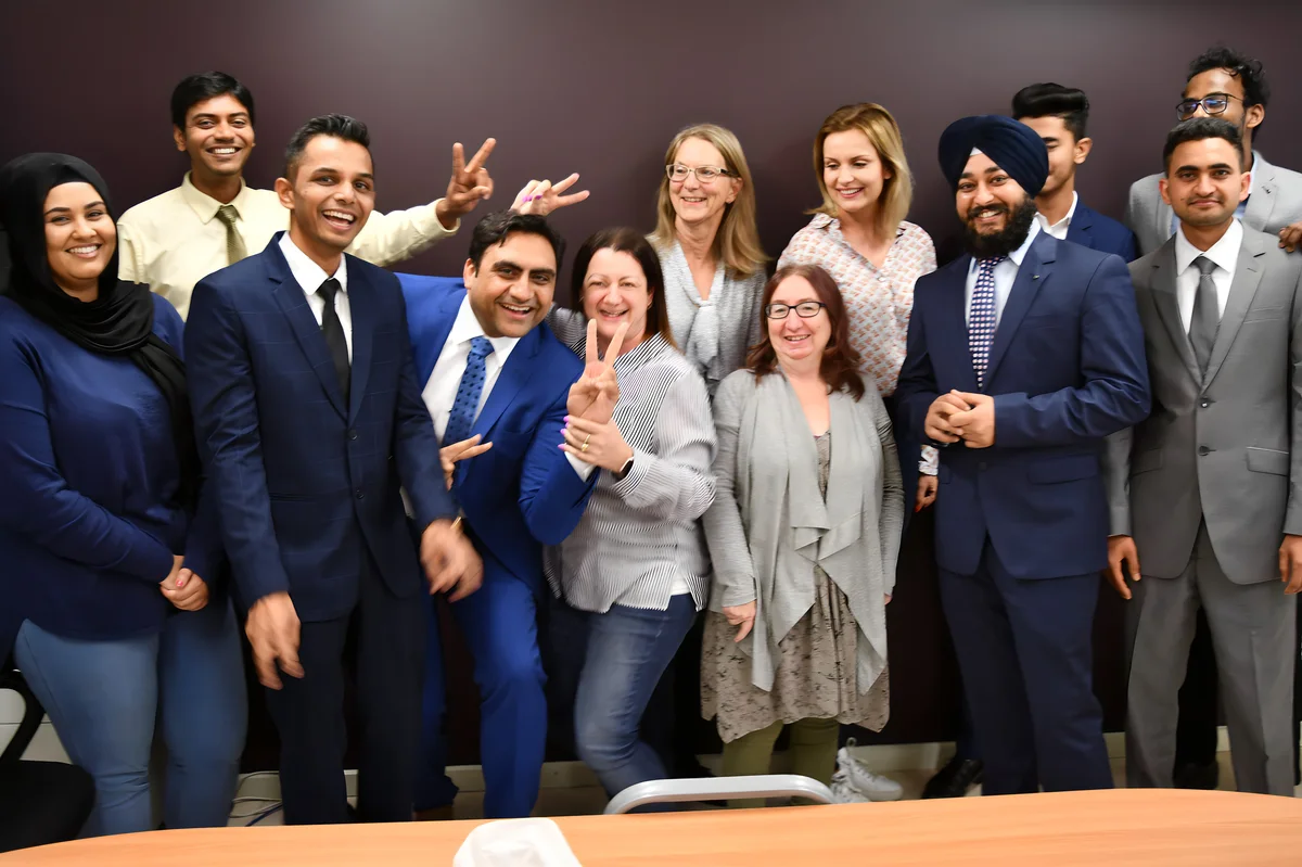 A diverse group of professionals pose for a celebratory photo, showcasing Sukh Sandhu's commitment to teamwork.