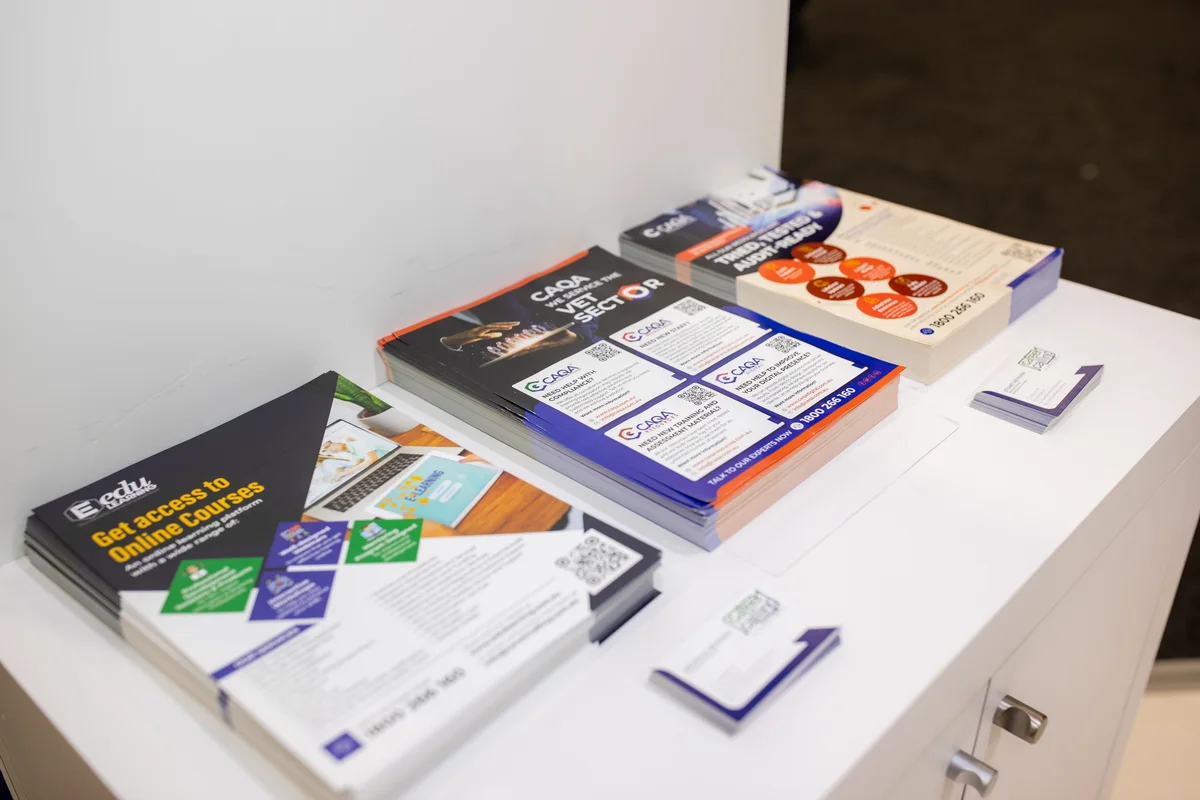 Informational booklets and flyers are displayed on a table, showcasing available online courses for the VET sector.