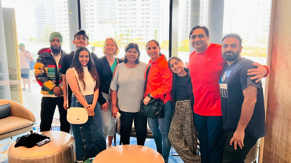 A group of people pose for a photo indoors, representing the team behind Sukh Sandhu's compliance services.