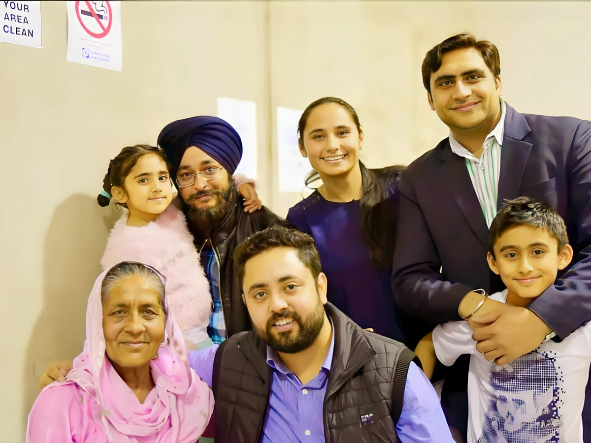 A multigenerational Sikh family poses for a portrait indoors, reflecting Sukh Sandhu's personal values.