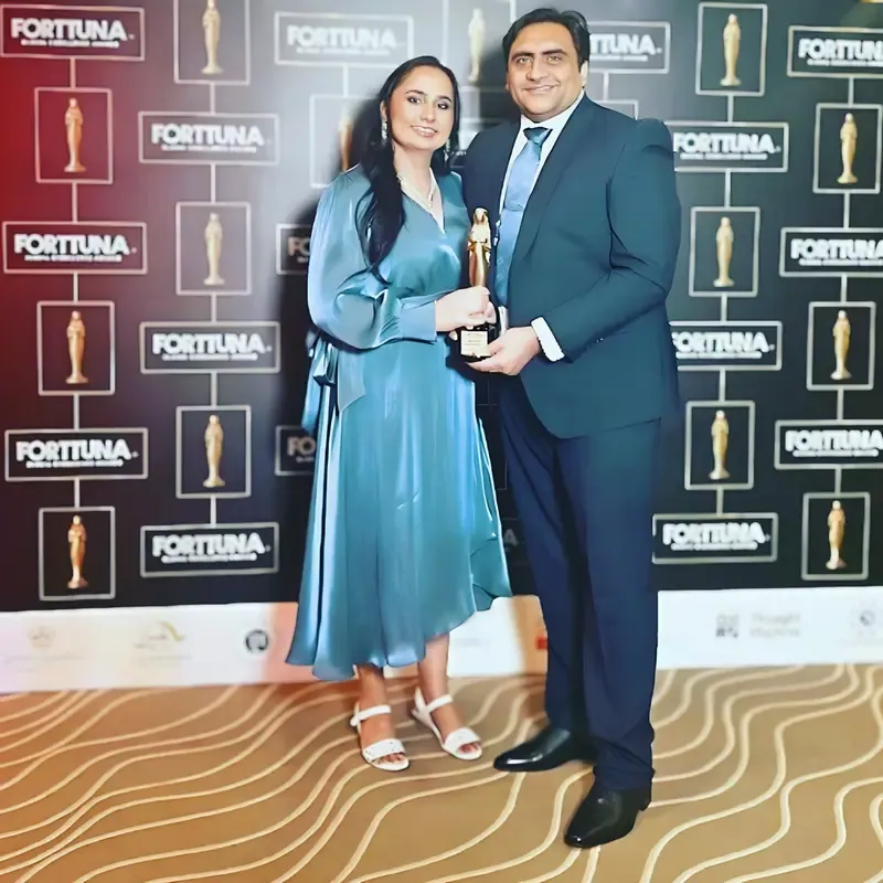 A couple receives an award from Fortuna, recognizing Sukh Sandhu's achievements.