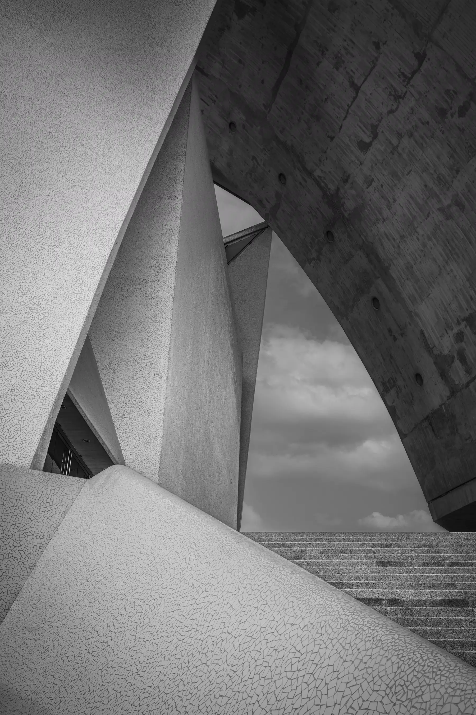 Concrete architecture frames a cloudy sky above outdoor steps, illustrating quality assurance.