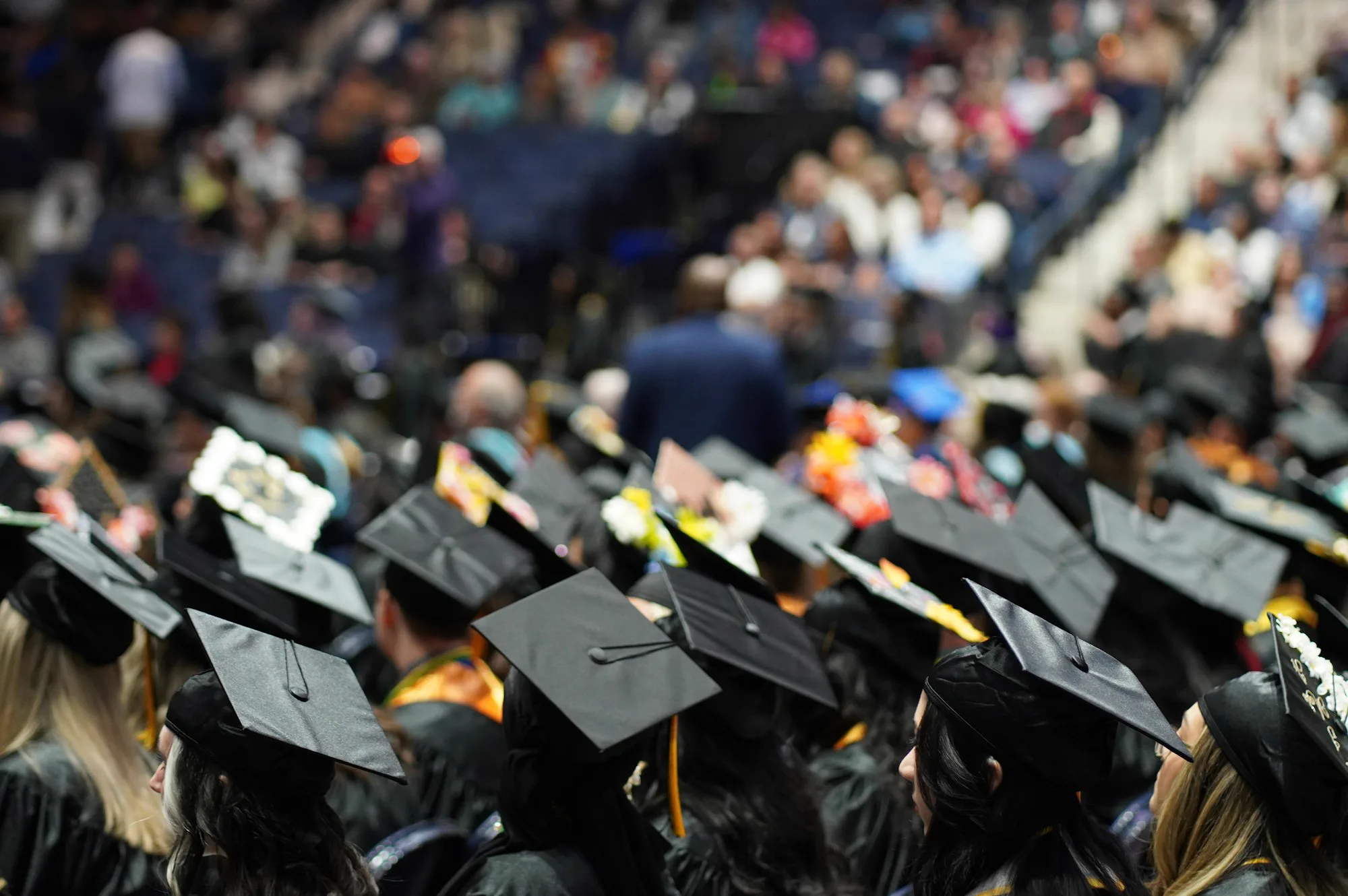 Graduates celebrate at a commencement ceremony, highlighting Sukh Sandhu's work in professional development.